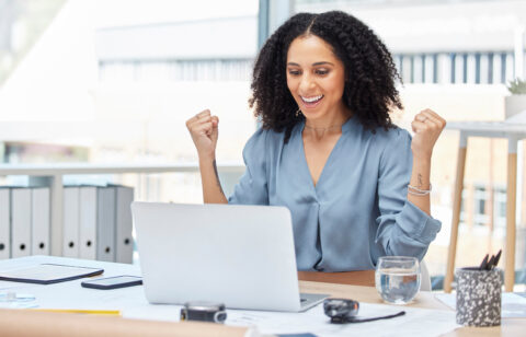 business woman celebrating winning by her computer