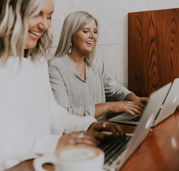 Two women looking and typing on computers