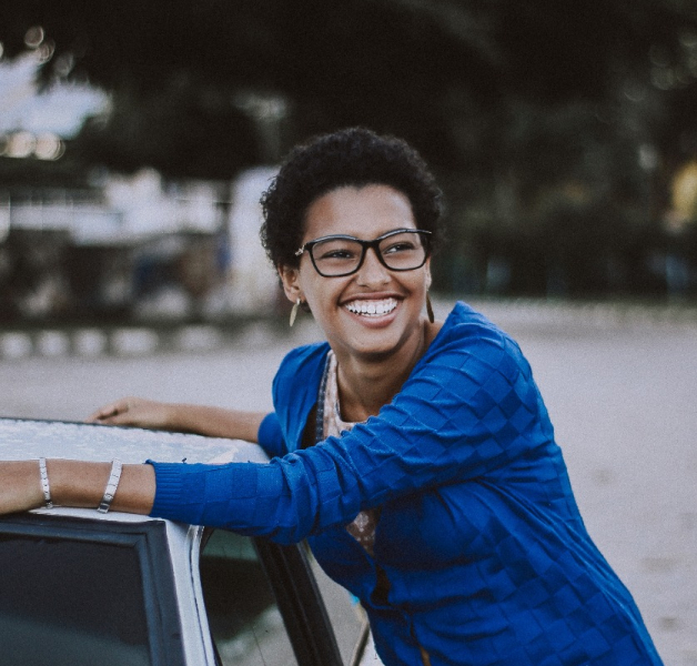 woman in blue by car smiling