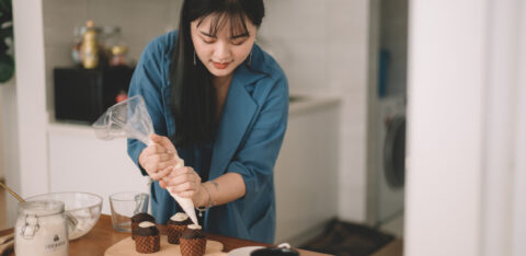 Asian Chinese female piping frosting on cupcake