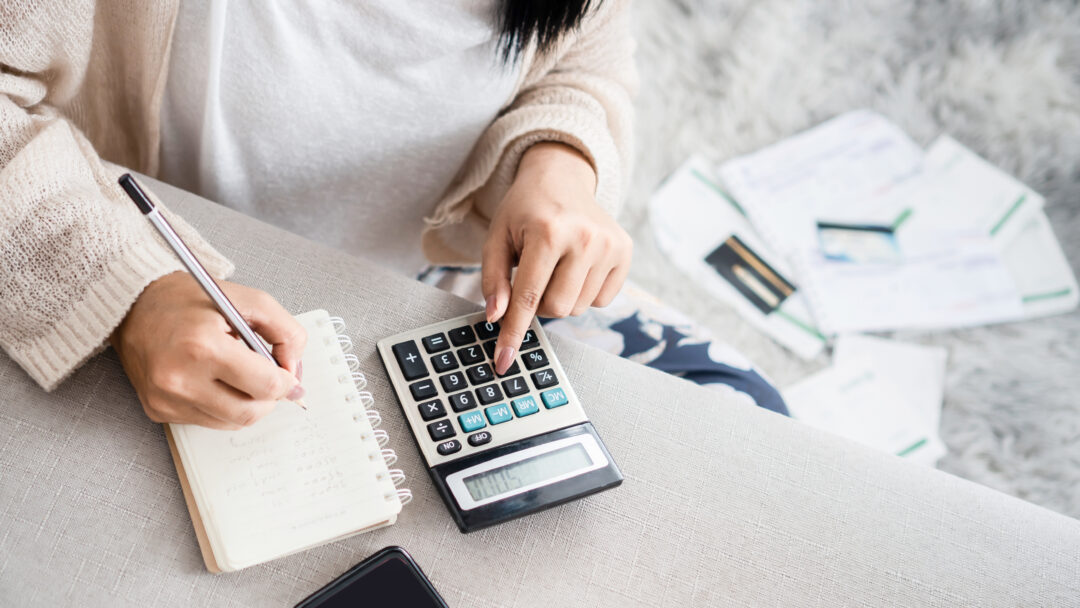 Woman looking at finances with calculator and notepad