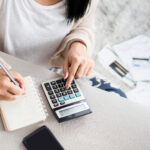 Woman looking at finances with calculator and notepad