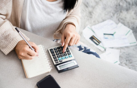 Woman looking at finances with calculator and notepad