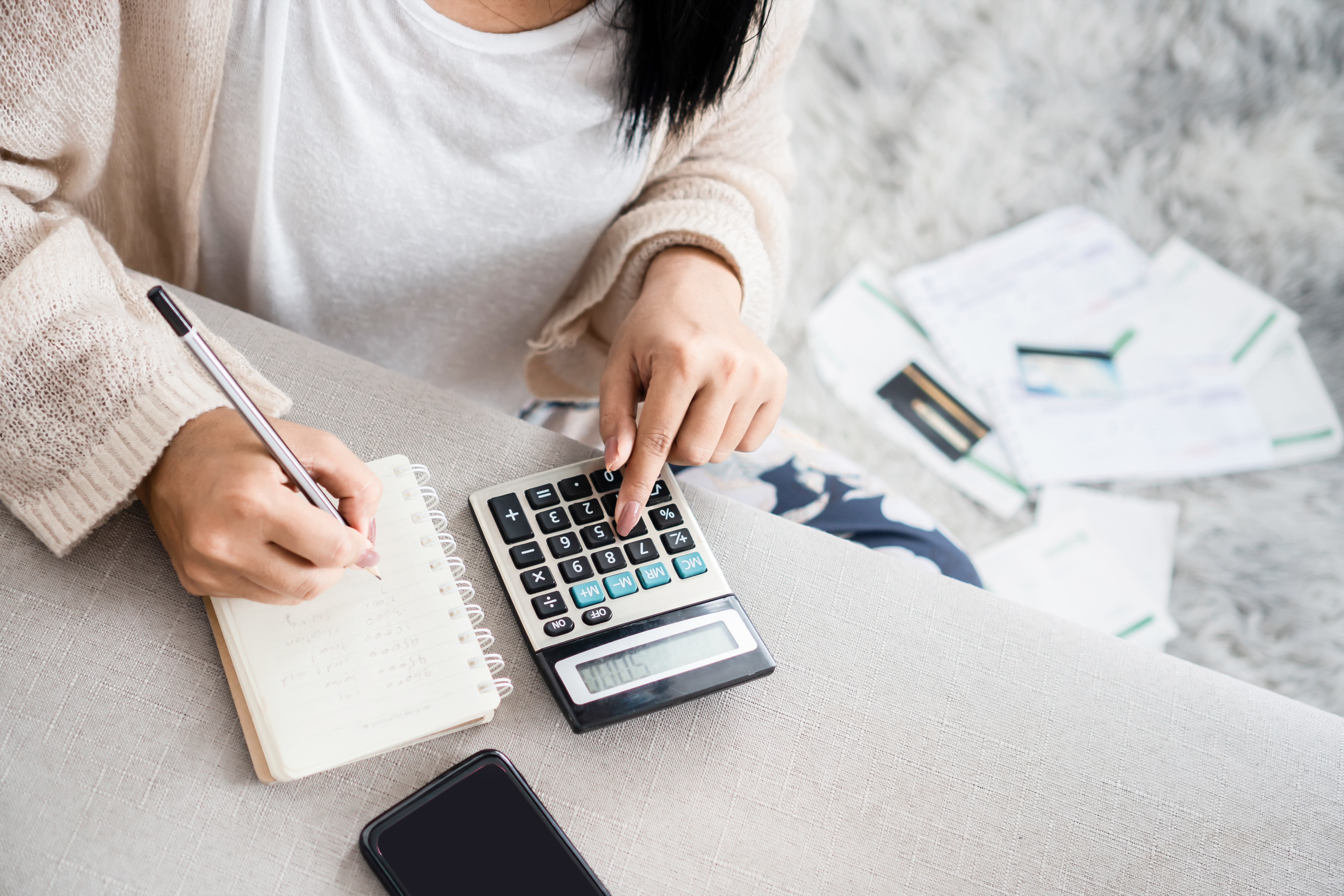 Woman looking at finances with calculator and notepad