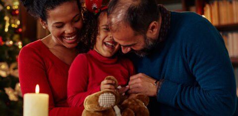 smiling child with parents with holiday decor in background