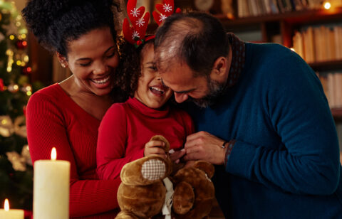 smiling child with parents with holiday decor in background