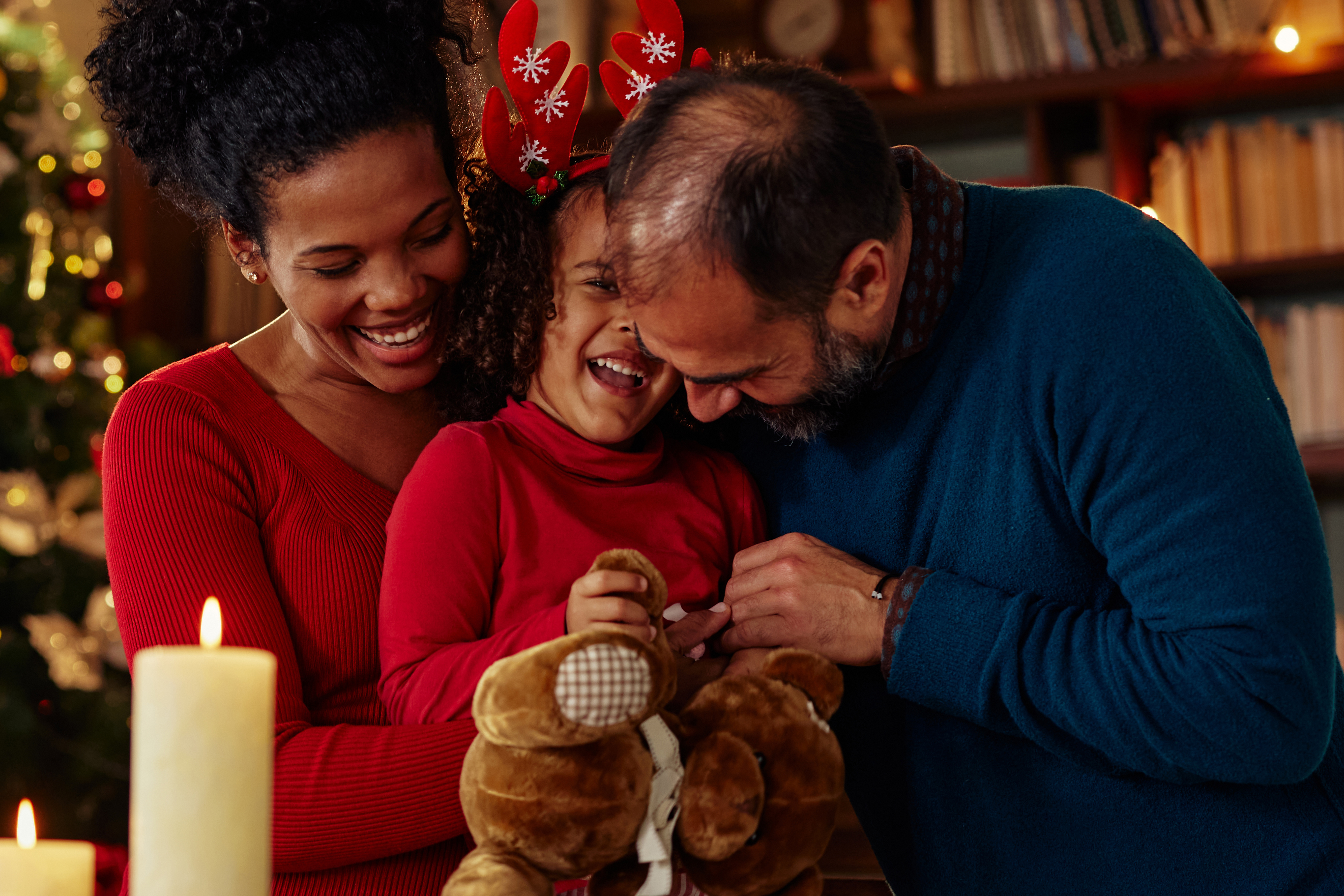 niño sonriente con sus padres con decoración navideña de fondo