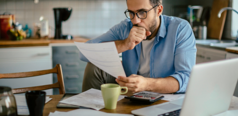 man looking at past due bills at table