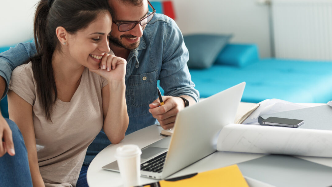 Smiling couple working on financial planning or budgeting together on a laptop.